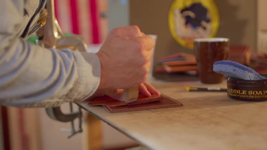 A man makes leather wallets in a workshop
