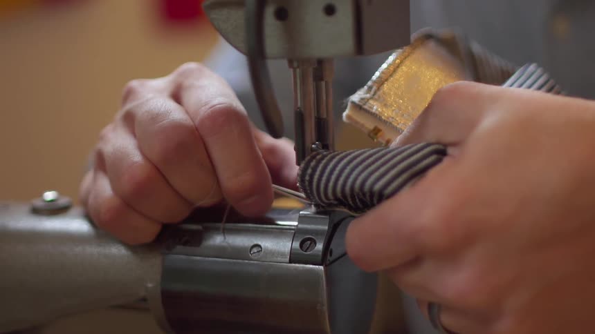 The person is slowly feeding thread into the machine