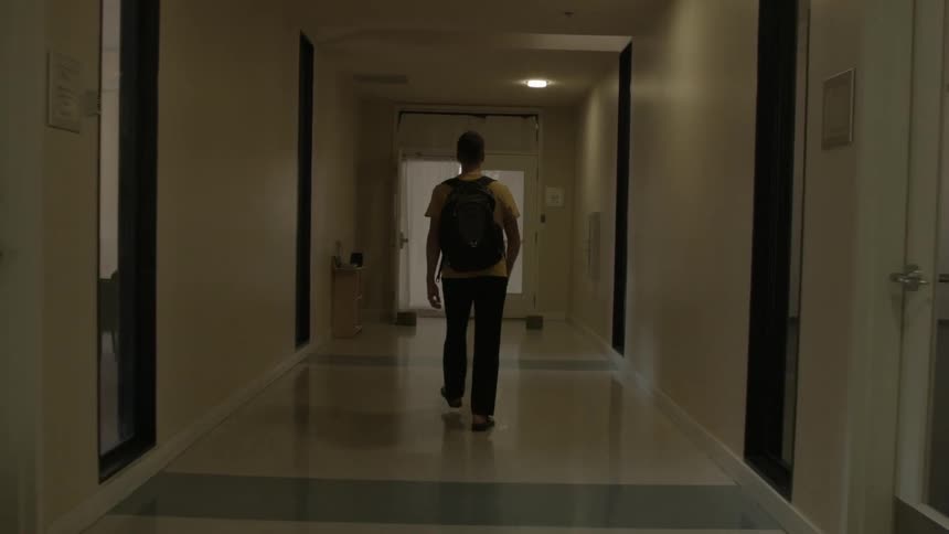 A person wearing a backpack walks down a hallway