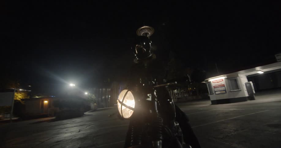 A motorcyclist is stopped in a parking lot at night