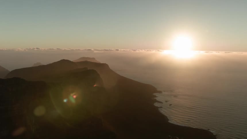 The sun sets near a mountain