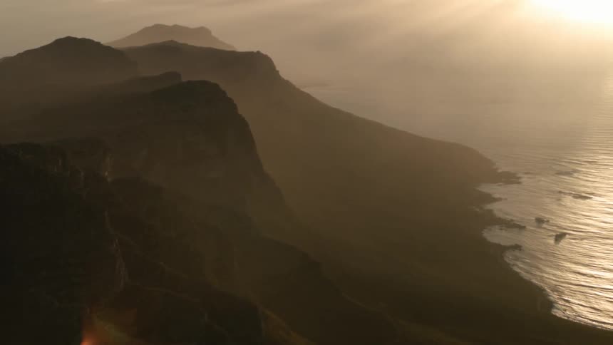 The sun sets over a coastal mountain range