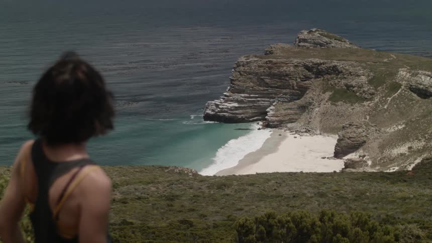A woman looks out towards a beach