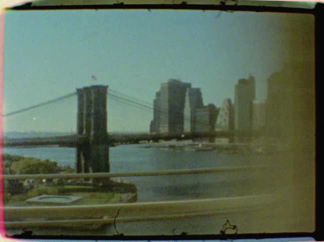 An old video clip of a suspension bridge as seen from a moving vehicle while crossing another bridge