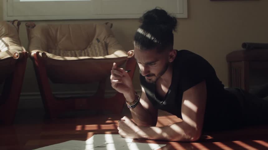 A man leans over with a pen writing
