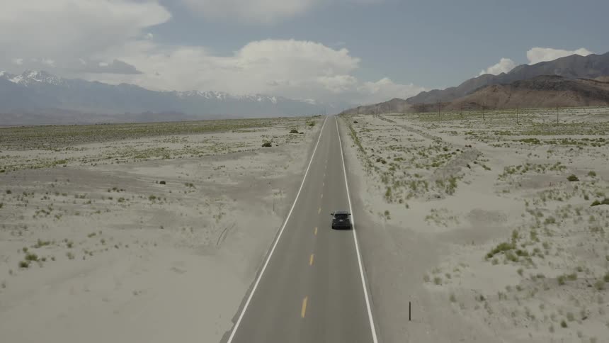 A car drives on a rural desert road