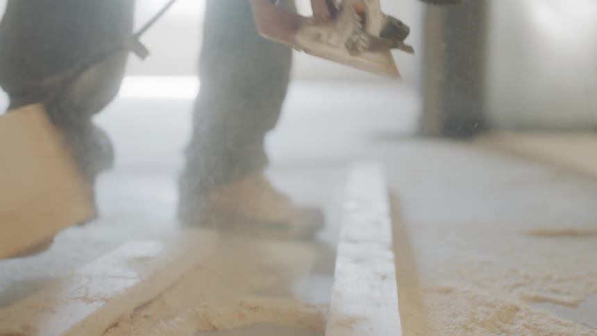 Man is cutting piece of wood with circular saw