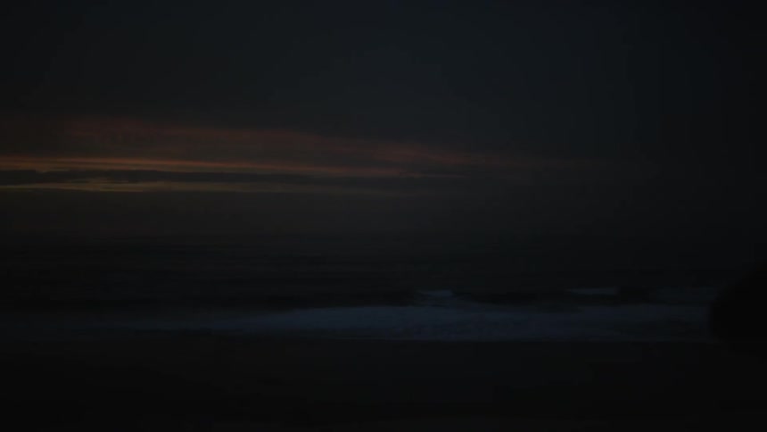 Ocean waves break and splash onto the beach at sunset