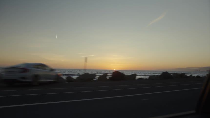 Vehicle travels down a highway near the ocean