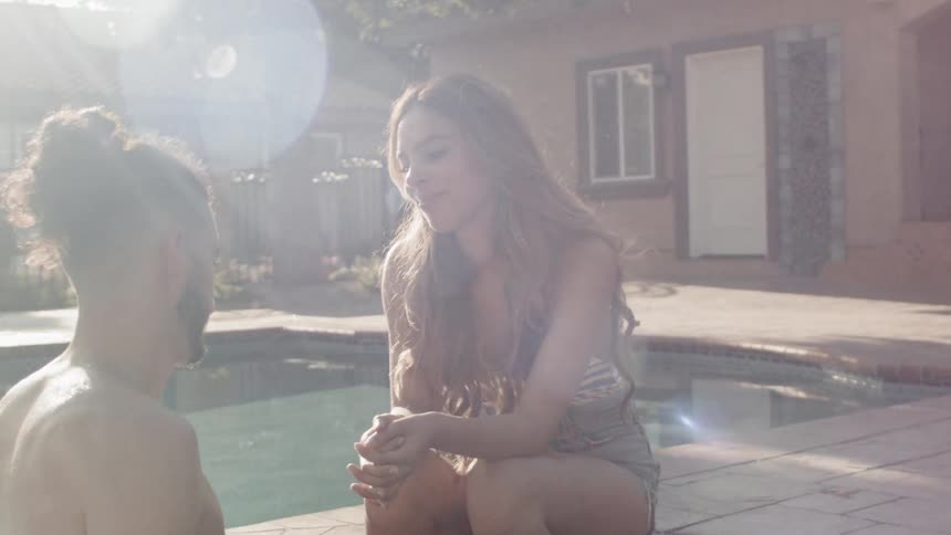A man walks to a woman by the pool