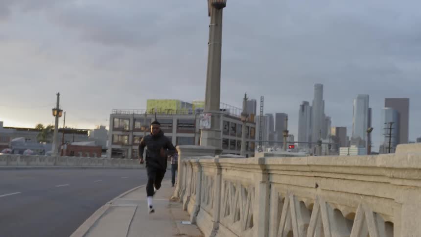 Man is sprinting down city street on cloudy day