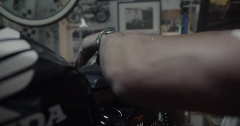 A man puts a seat on a motorcycle in a workshop