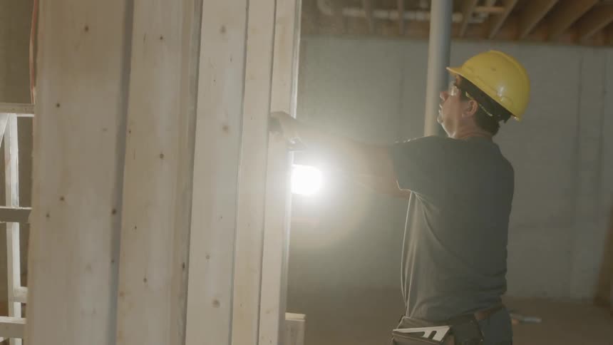 A builder hammers wood framing