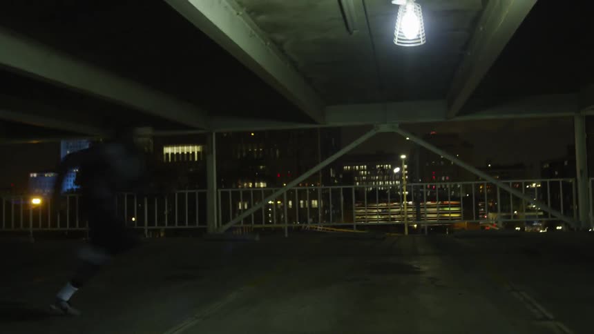 A man runs in a parking garage at night