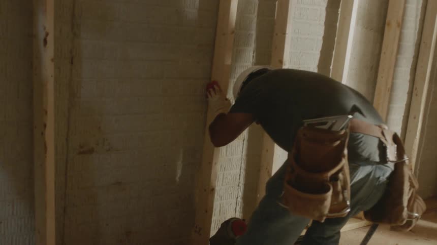 A worker uses a nail gun at a construction site