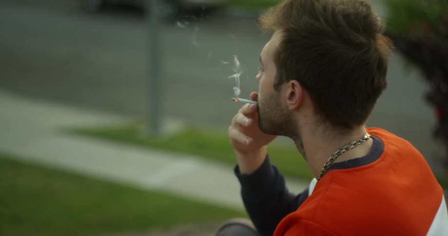 A man smokes a cigarette alone on a roof