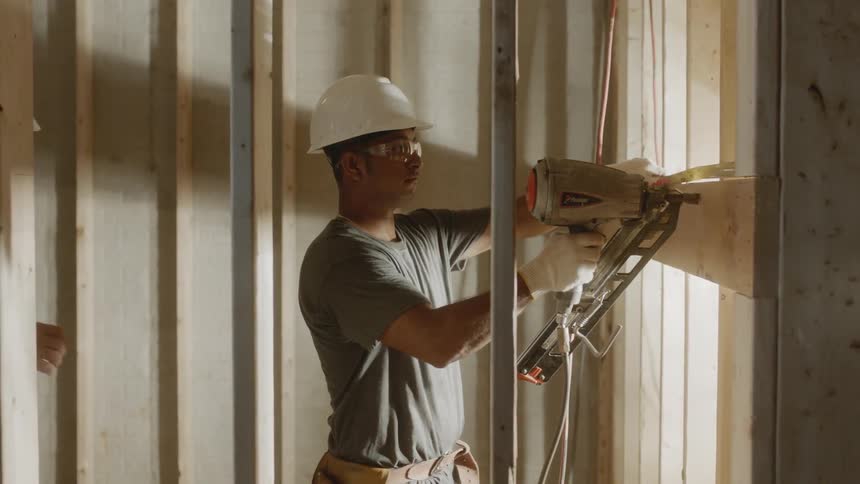 A construction worker uses a nail gun