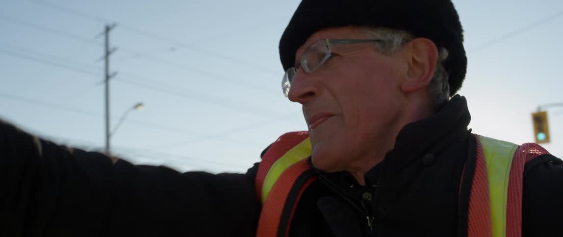 Man wearing a vest smiles as he moves his arms
