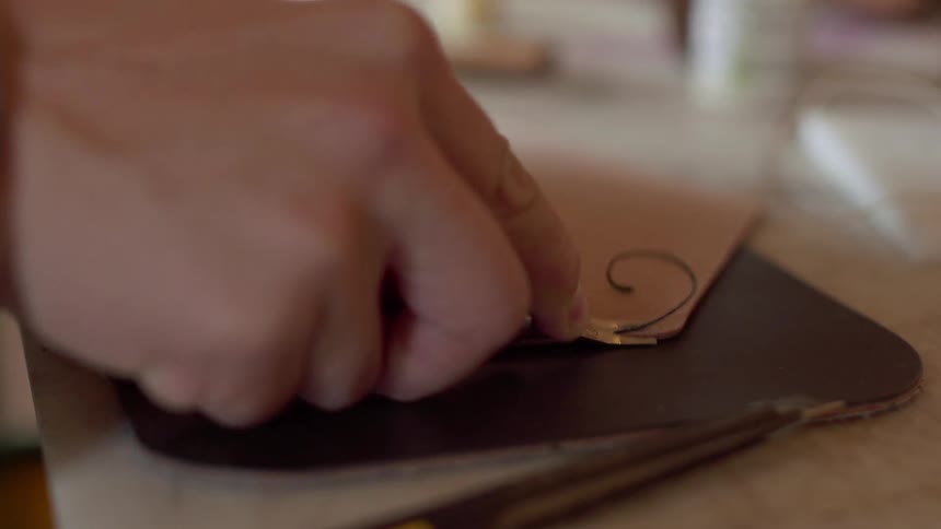 A man makes leather wallets in a workshop