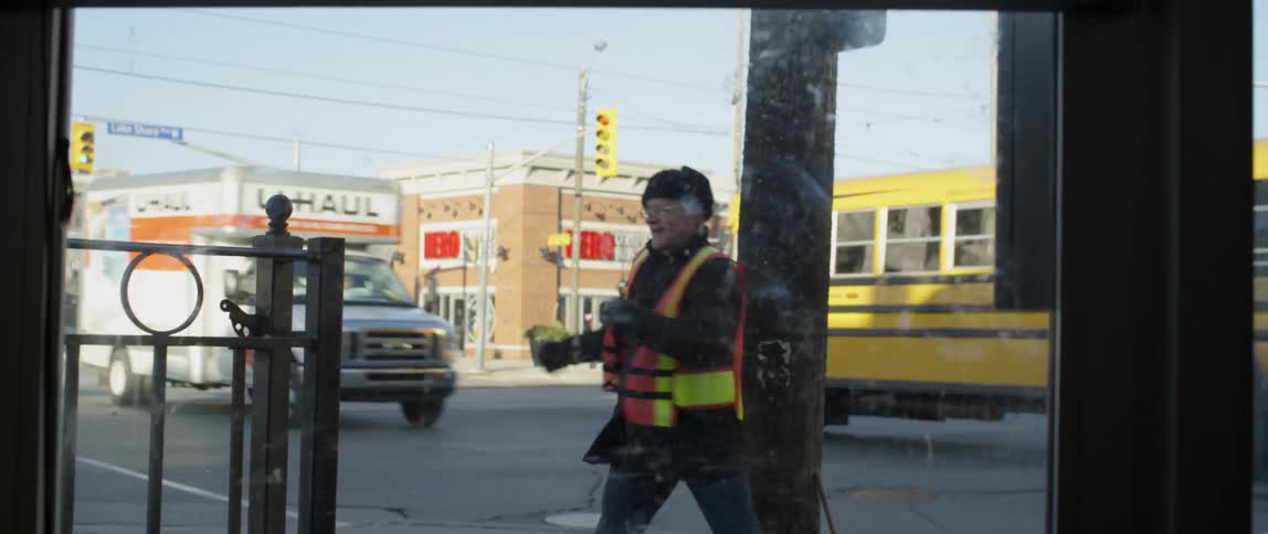Man wearing an orange vest does twists while standing on the sidewalk