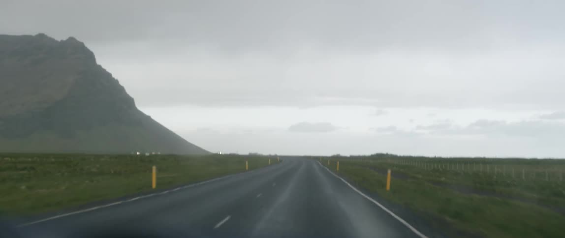 Windshield wipers go back and forth as a vehicle travels on an empty road