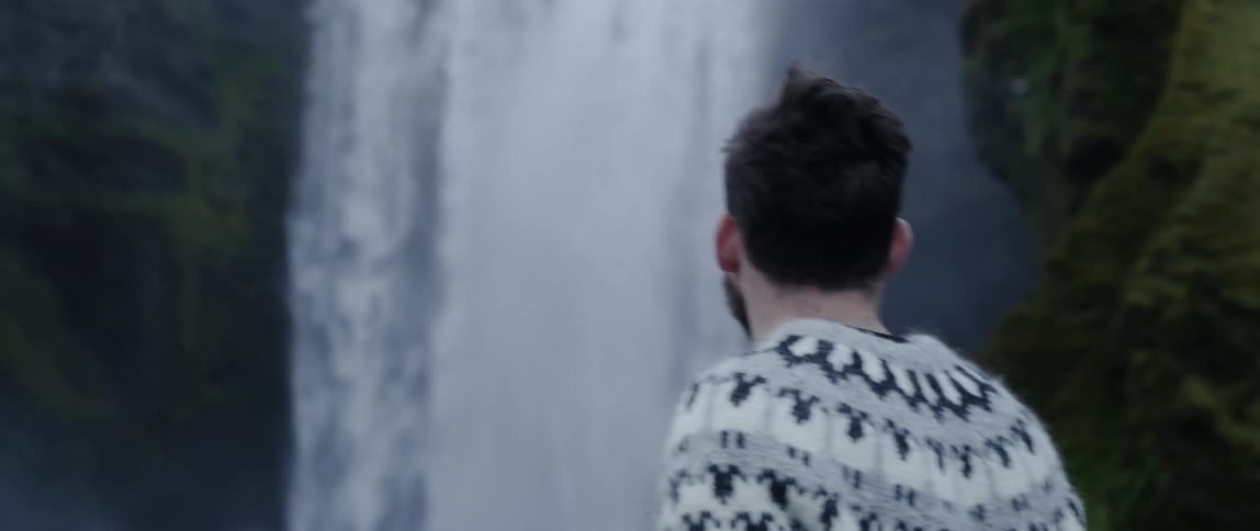 A man walks towards a waterfall