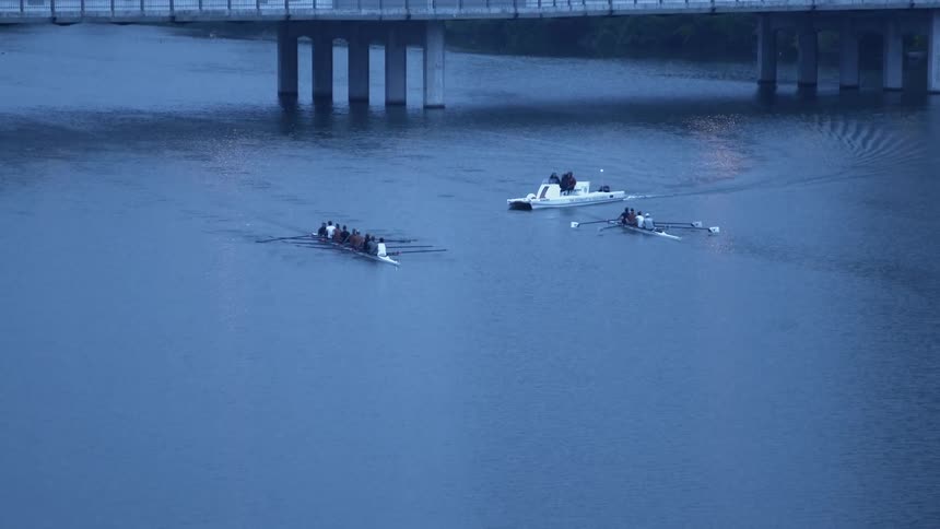 A boat passes two rowing crew shells