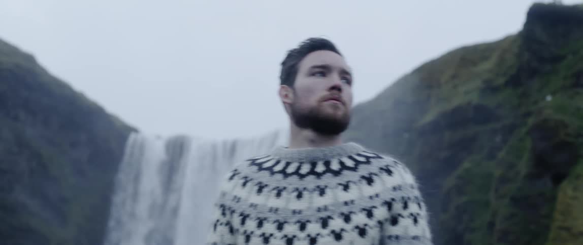 Man is standing in wilderness area in front of waterfall