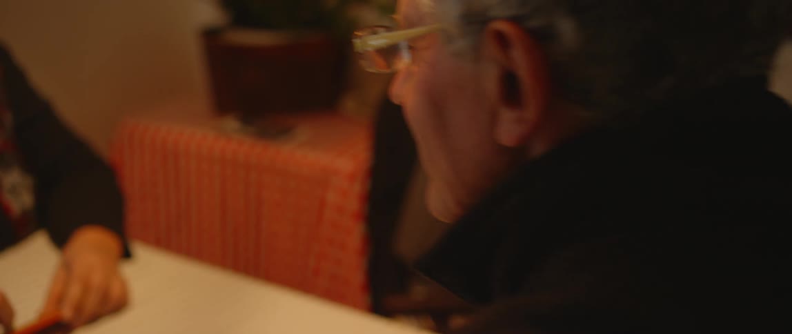 An elderly couple sit at a table