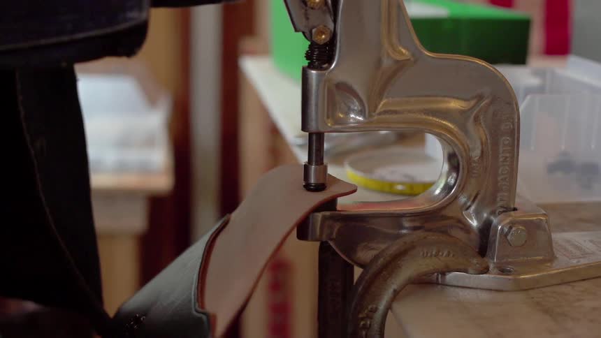 A man makes leather wallets in a workshop