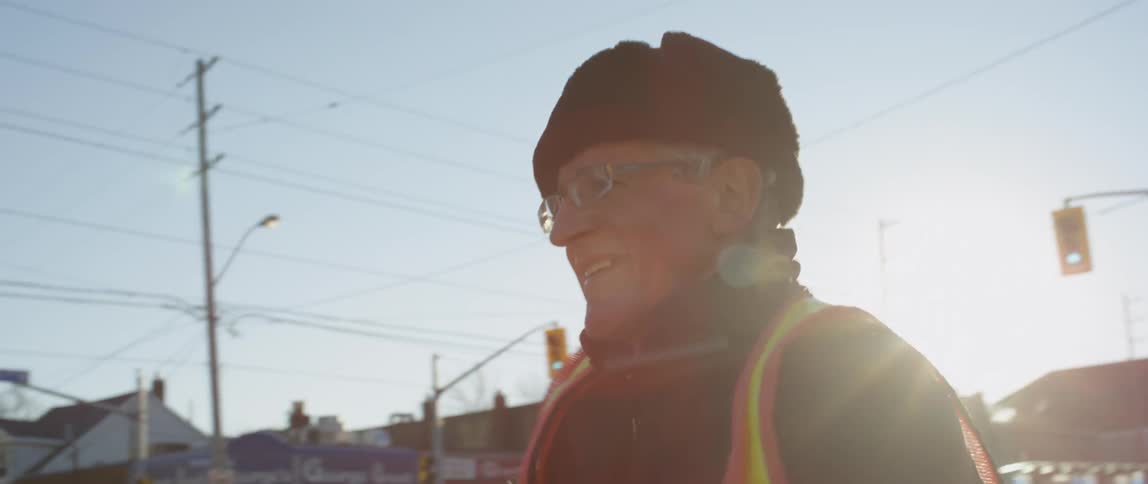 Elderly man dances outside in the city on a sunny day