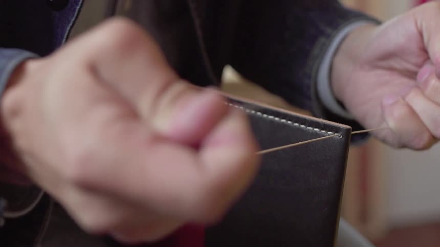 A man stitches leather