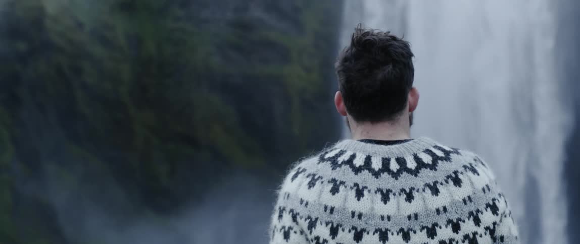 Man hikes near a large waterfall