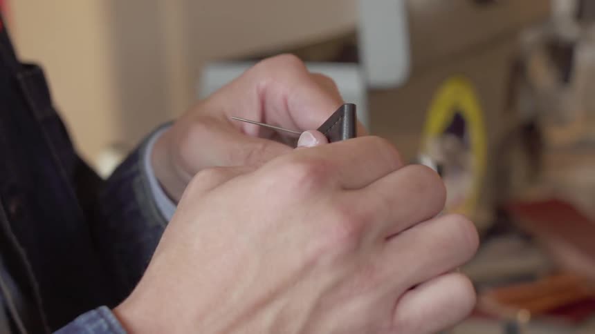 A man stitches leather