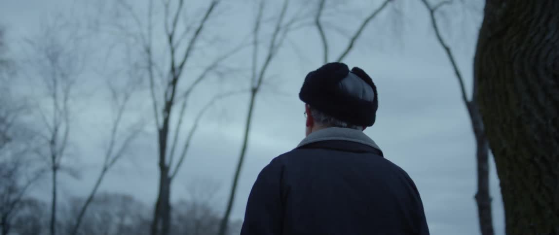 A man walks outside on a cold and cloudy evening