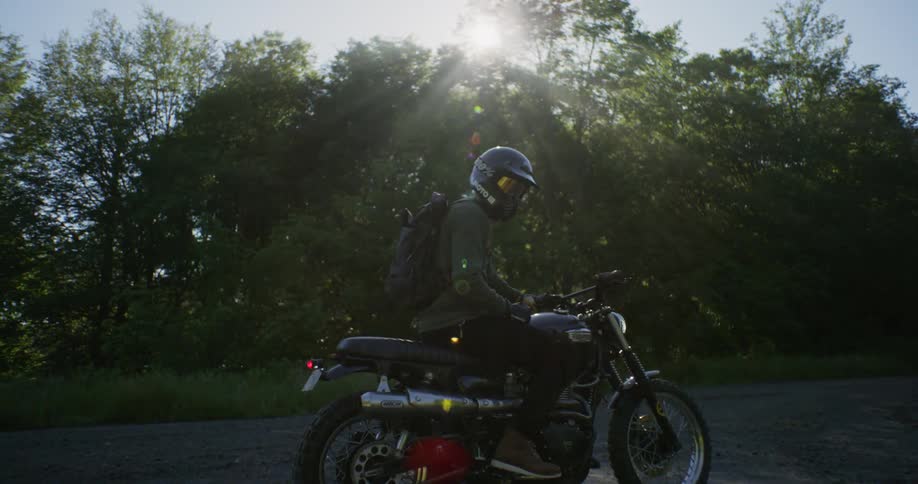 The sun shines on a rider sitting on a motorcycle