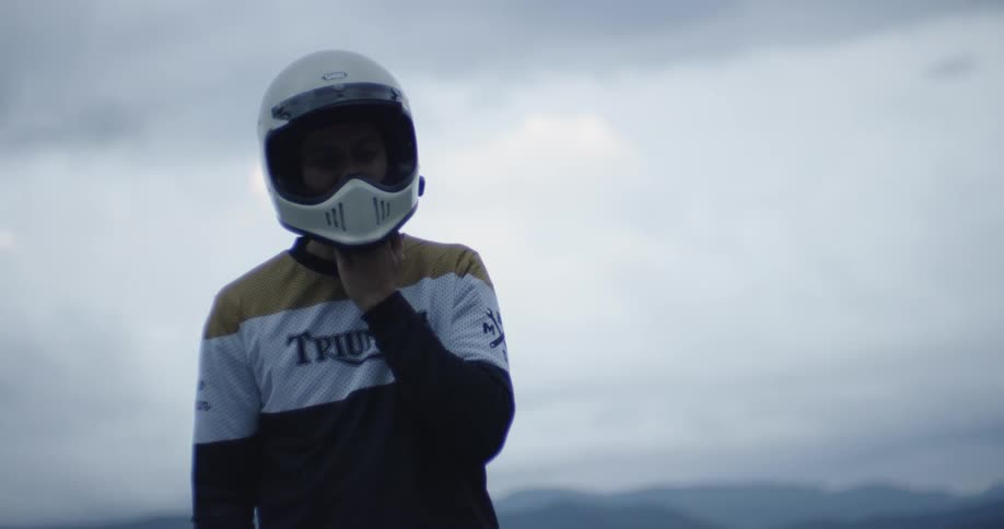 A motorcyclist adjusts his helmet