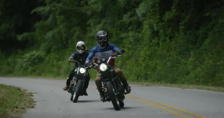 Two motorcyclists ride in a zigzag pattern