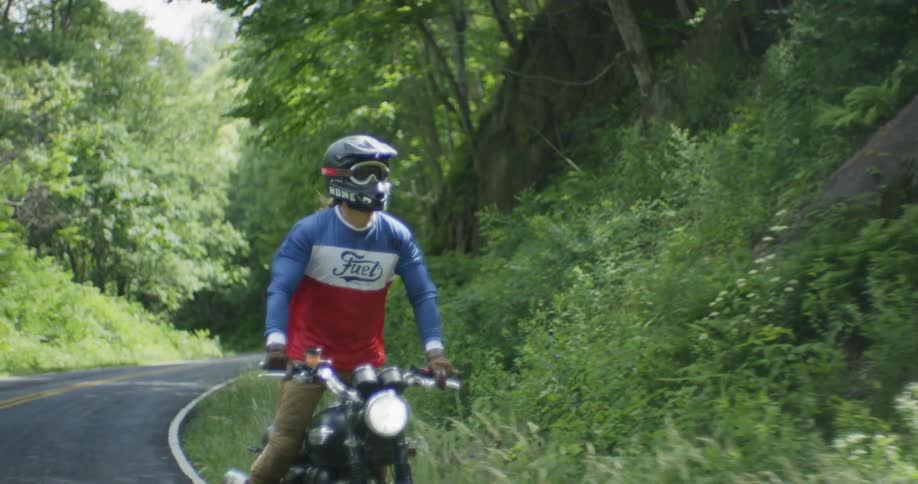 A man stands up on a motorcycle