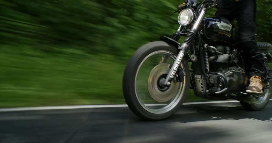 A man stands up on a motorcycle