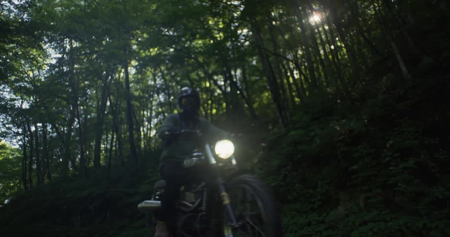 A motorcyclist rides on a woodsy road