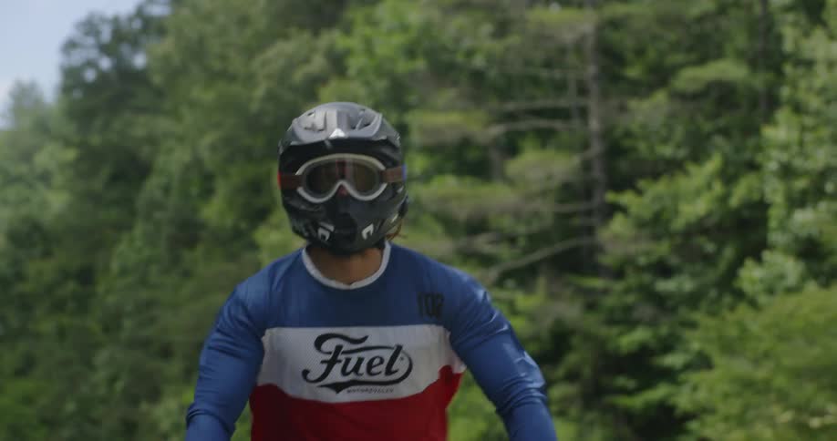 A man rides a motorcycle by the woods