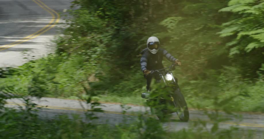 Two motorcyclists drive on a winding road