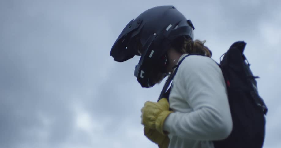 A man stands outside with a motorcycle helmet on
