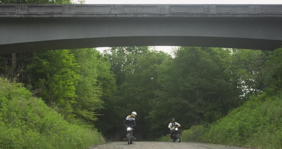 Two motorcyclists ride on a dirt path