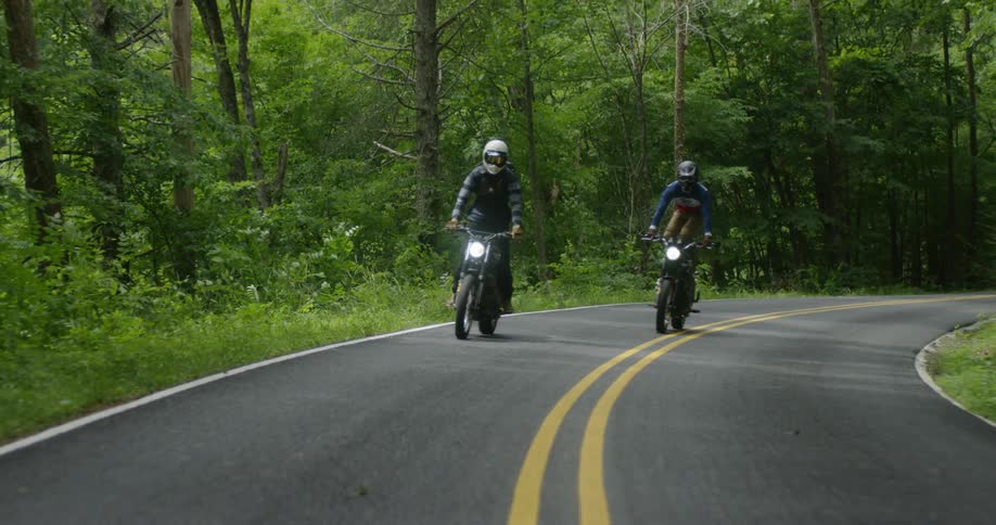 Motorcyclists ride in a forest