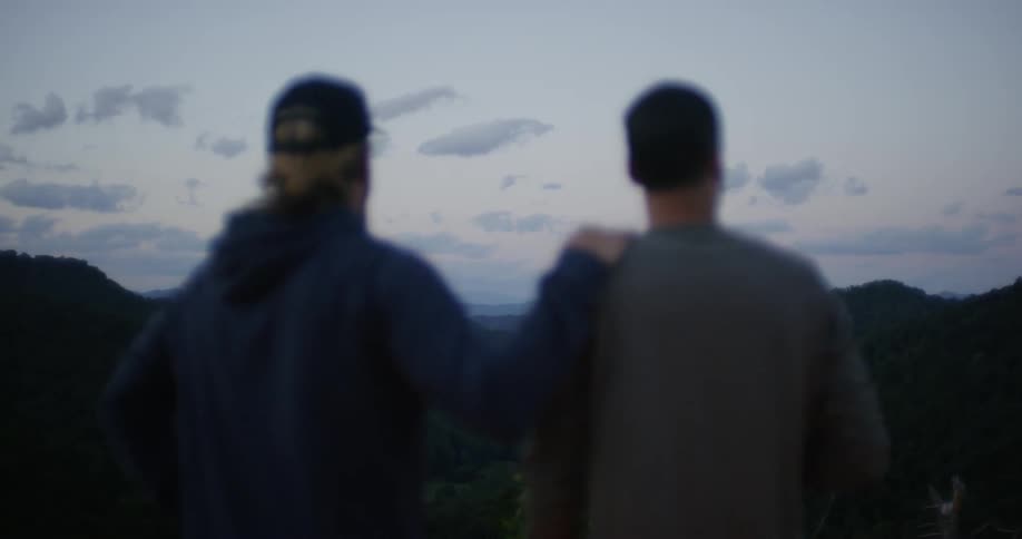 Two men stand atop a mountain