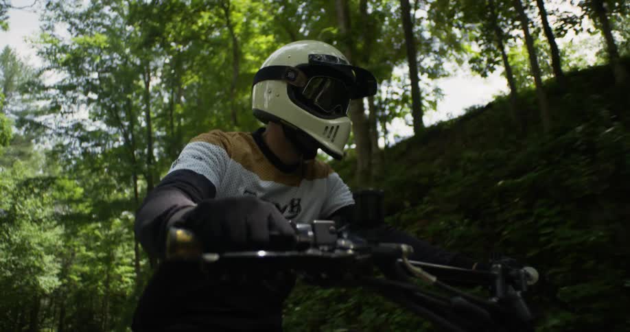 A motorcyclist rides through a forest