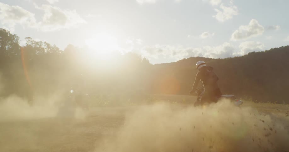 A motorcyclist kicks up dust while spinning in dirt