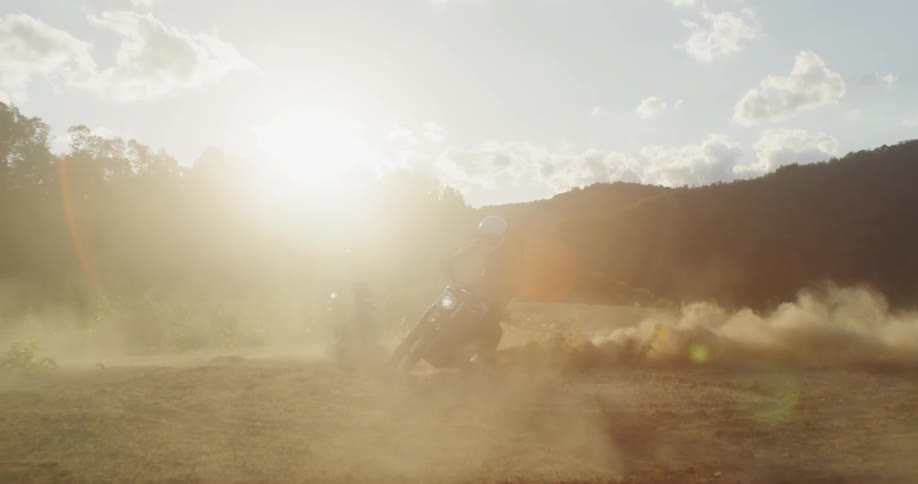 A motorcyclist kicks up dust while spinning in dirt